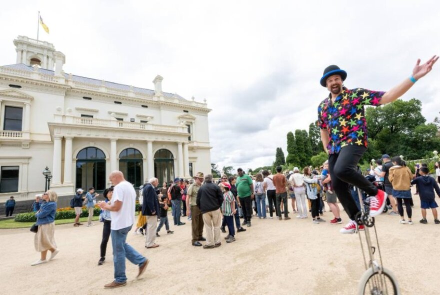 Street performers and crowds outside the colonial-era white stucco Goverment House.