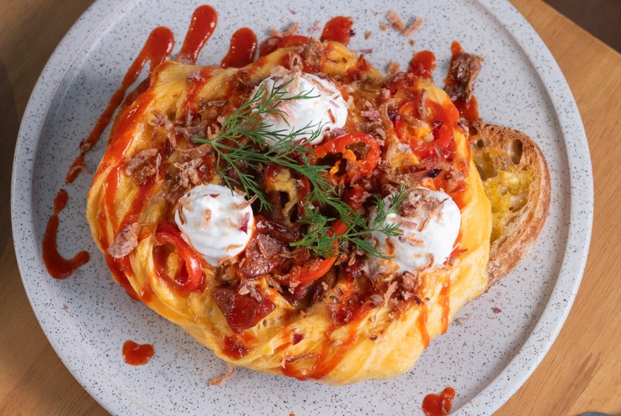 Looking down at chilli scramble eggs on toast on a plate.