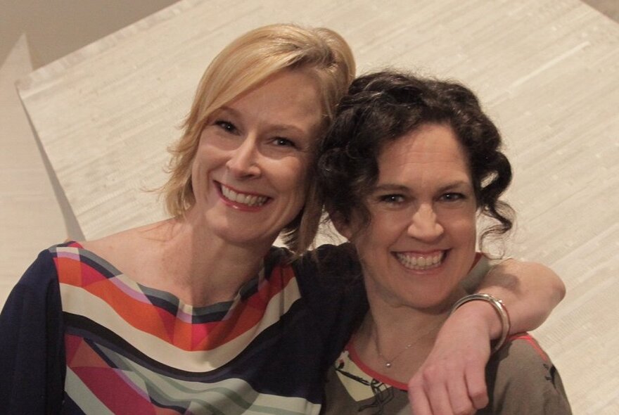 Annabel Crabb and Leigh Sales with their heads close together, both smiling and facing the viewer.