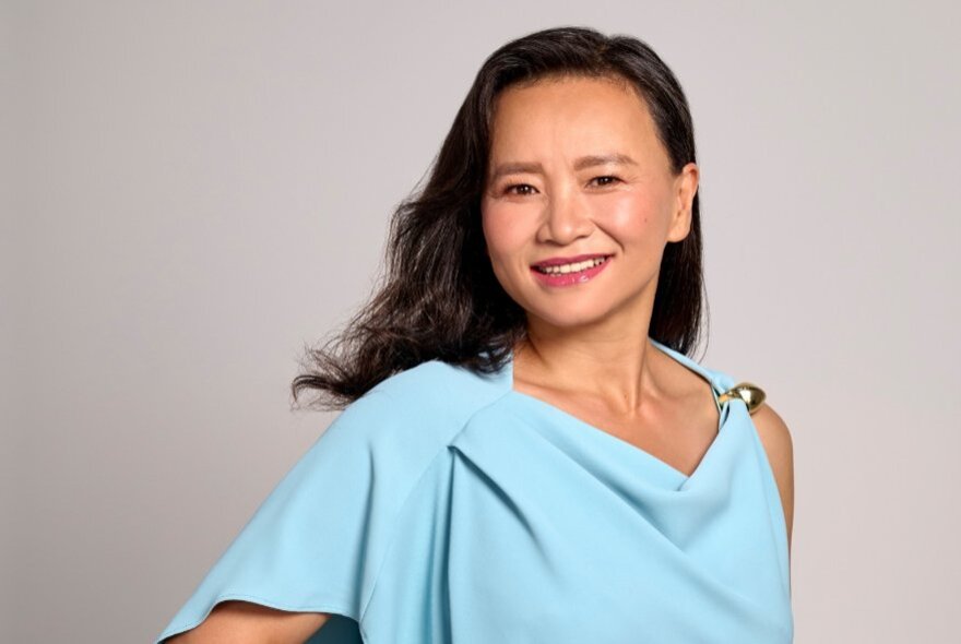 Journalist Cheng Lei, wearing a loosely cut pale blue draped top. 