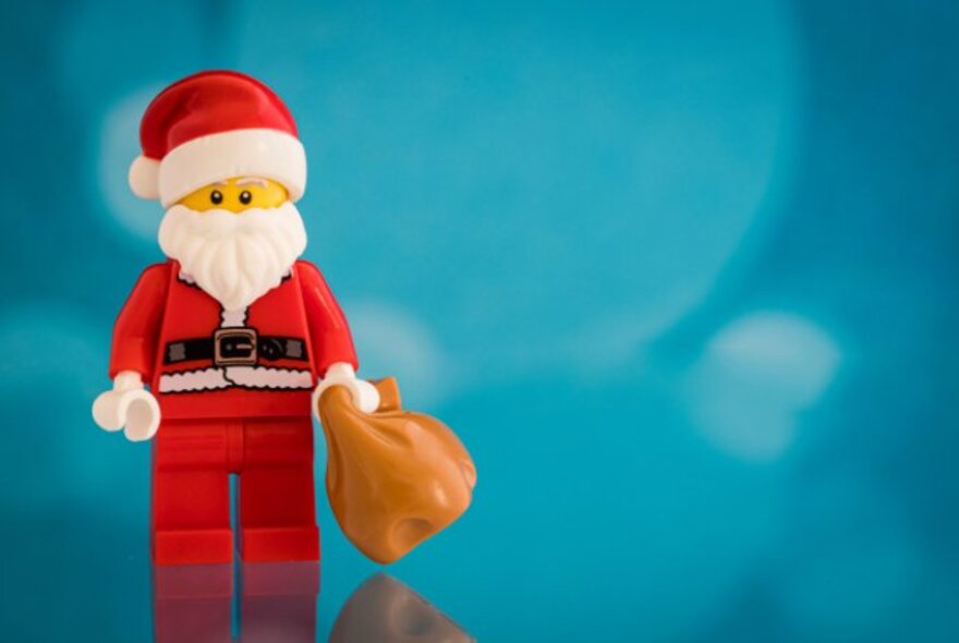 Santa Leggo toy holding a sack against a blue background.