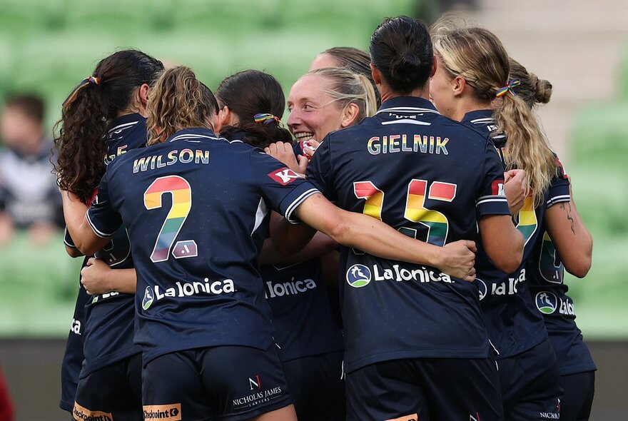 Women soccer players in a huddle on the ground during a match.
