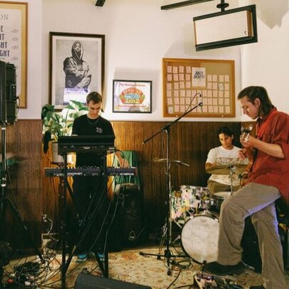 A trio of musicians playing instruments in a corner of a pub. 