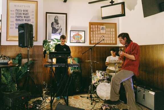 A trio of musicians playing instruments in a corner of a pub. 