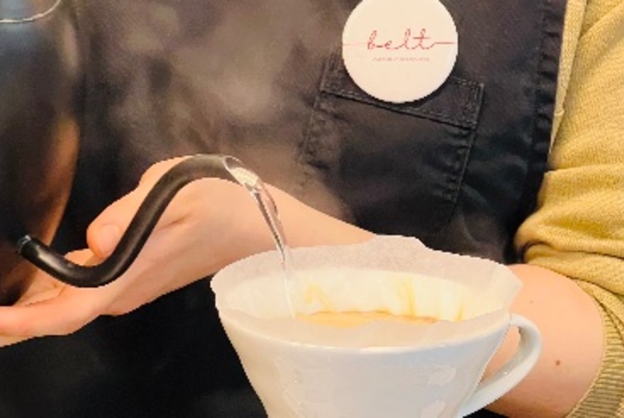 A person making a pour over coffee using filter paper.