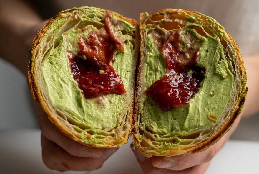 A matcha and strawberry filled croissant sliced in half.