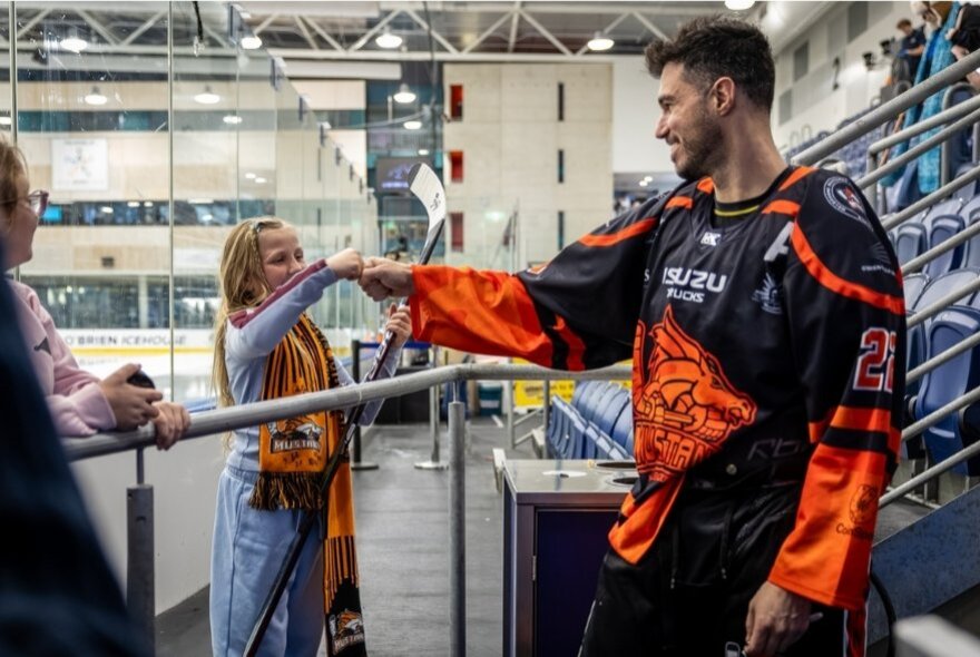 An ice hockey player knuckle-bumping a fan inside the stadium after a game. 