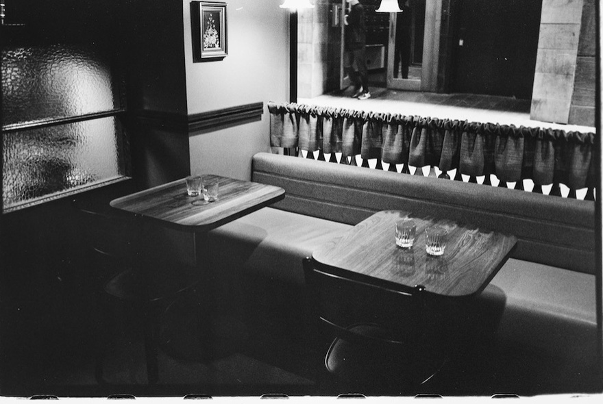 Empty tables and bench seating in a curtained cafe.