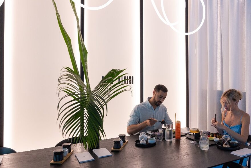 Two friends are eating dumplings in a modern restaurant