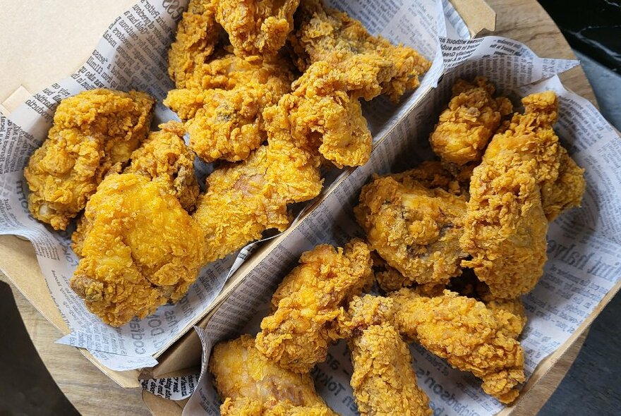 Two open cardboard takeaway containers of crispy fried chicken pieces. 