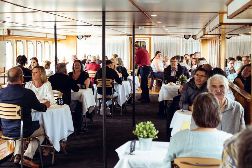 Diners seated at tables on a boat during a lunch cruise.