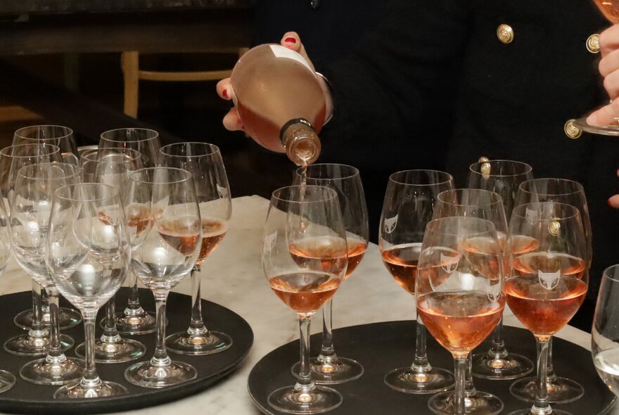 A waiter pouring champagne into glasses at an event. 