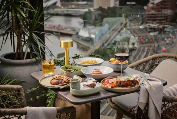 A table laden with food, plates and wine on a rooftop overlooking the railway tracks in Melbourne's CBD.