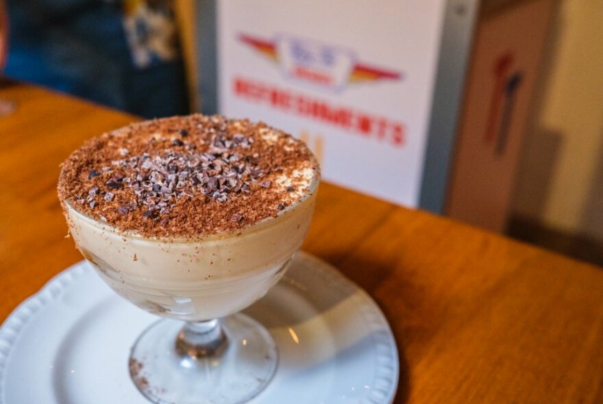 A glass bowl filled with tiramisu topped with chocolate shavings.