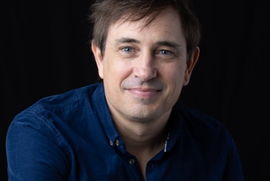 Author Trent Dalton looking relaxed and smiling with mouth closed. 