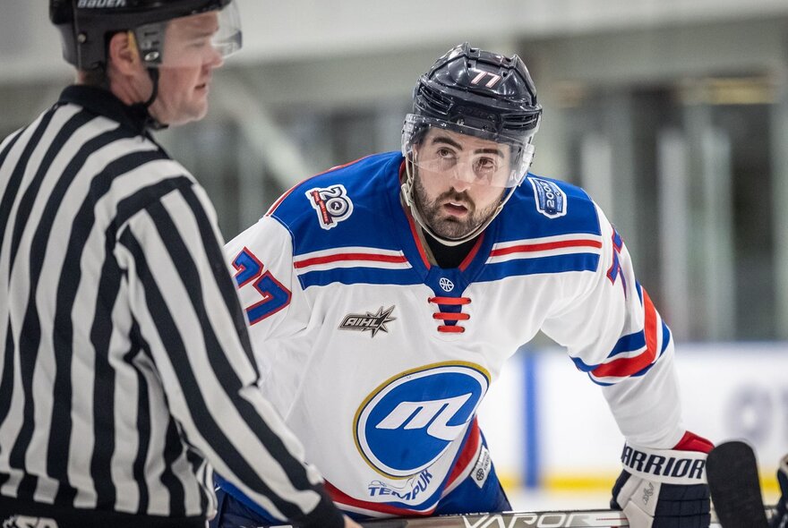An ice hockey player looking intently at a match referee.