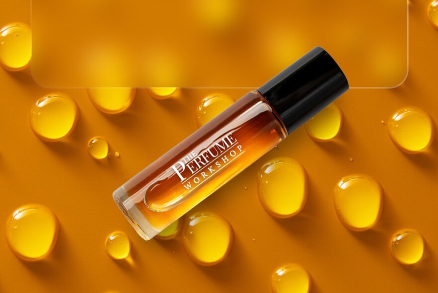 A perfume bottle next to golden droplets.