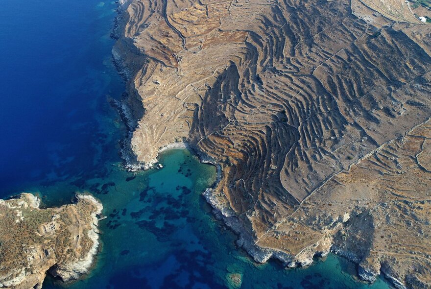 Aerial view of the coastline of an island, surrounded by blue sea.