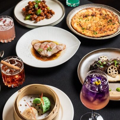 Array of Asian dishes and cocktails on a restaurant table.