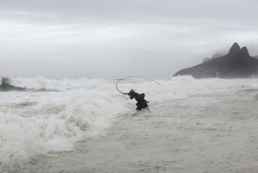 Artist Julius von Bismarck's black and white photographic artwork, Punishment #7, showing a man cracking a whip into the waves at a stormy beach.