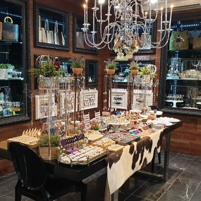 Interior of Mouche retail space with glass cabinet displays and a table featuring homewares and jewellery.