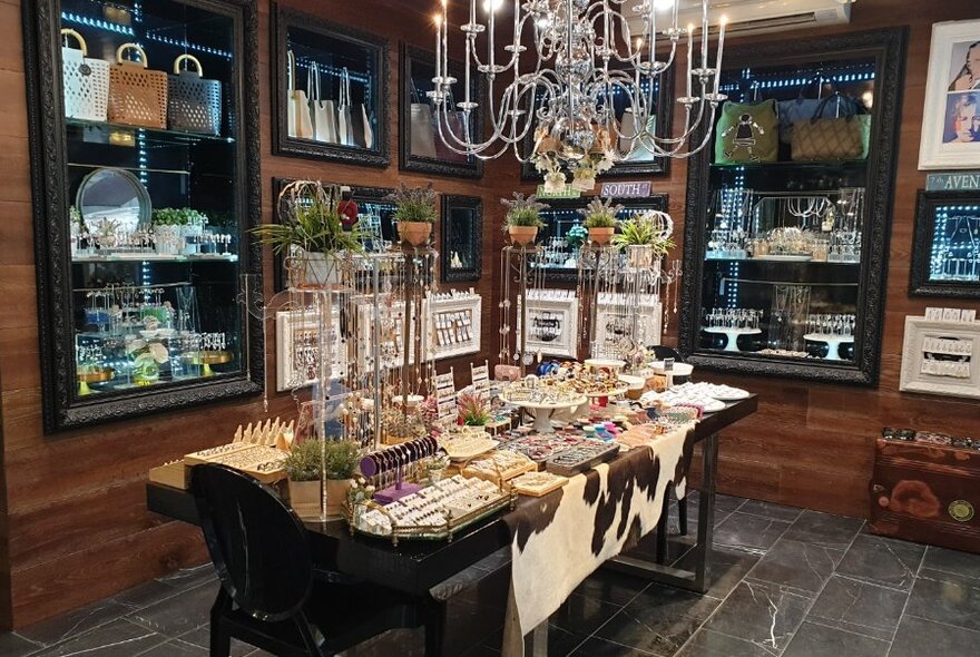 Interior of Mouche retail space with glass cabinet displays and a table featuring homewares and jewellery.
