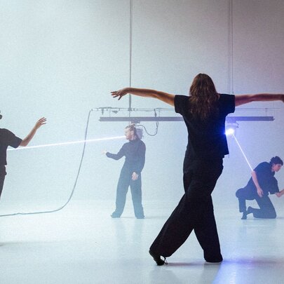Dancers in a studio space, some with strings on them looking like marionettes. 