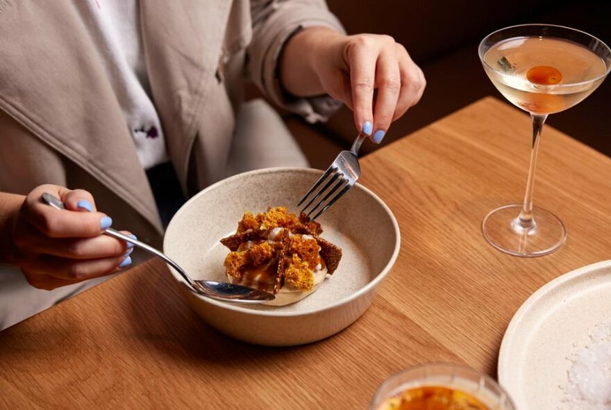 Woman eating a desert with a cocktail.