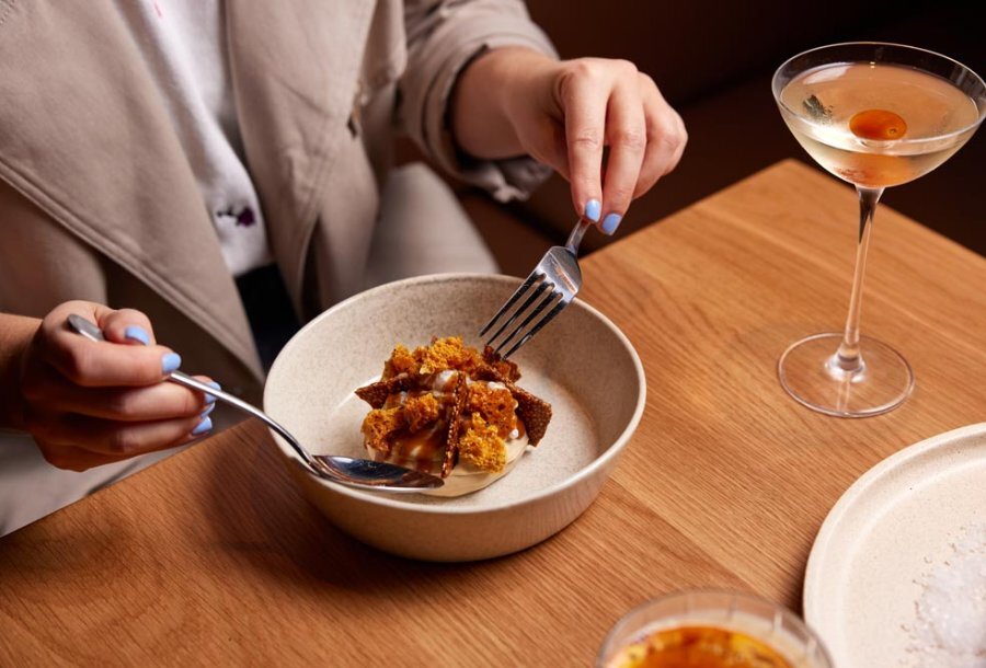 Woman eating a desert with a cocktail.