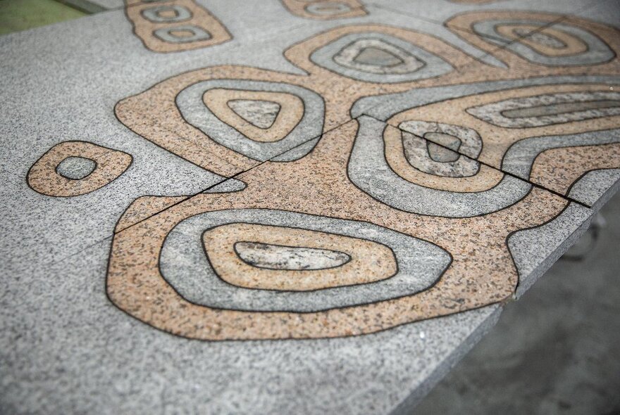 A grey speckled concrete surface, possibly a tabletop, with a curved and circular pale pink design incorporated into it.