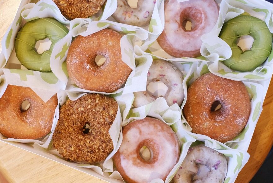 Tray of round donuts with holes, all with different types of icing.