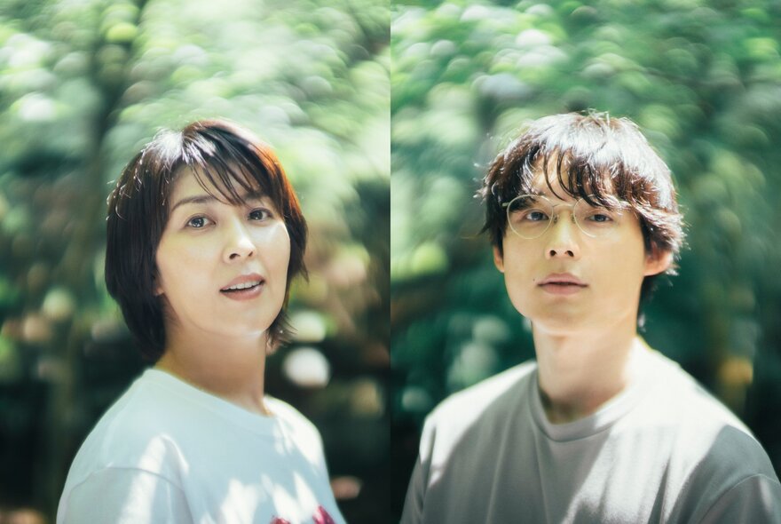 Japanese actors Takako Matsu and Hokuto Matsumura standing side by side outdoors against a green leafy backdrop, in a still from the romantic drama film 1st Kiss.
