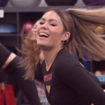 People dancing in an exercise class, hair flying, bending on one hip with feather boas.