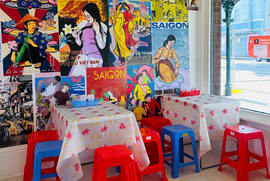 Plastic stools and tables in a small cafe with poster-lined wall.