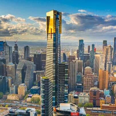 Gold-plated Eureka Tower skyscraper and cityscape against the city skyline and blue sky with clouds.