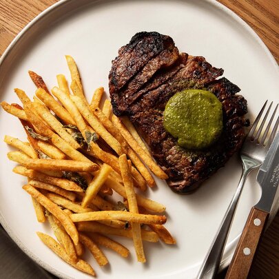 Steak and chips with a green butter sauce. 