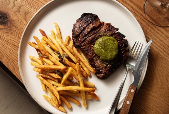 Steak and chips with a green butter sauce. 