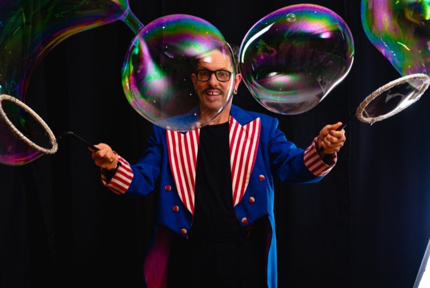 Performer wearing a coat with striped lapels, with a large bubble wand.