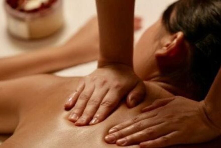 Two hands massaging a woman's back.