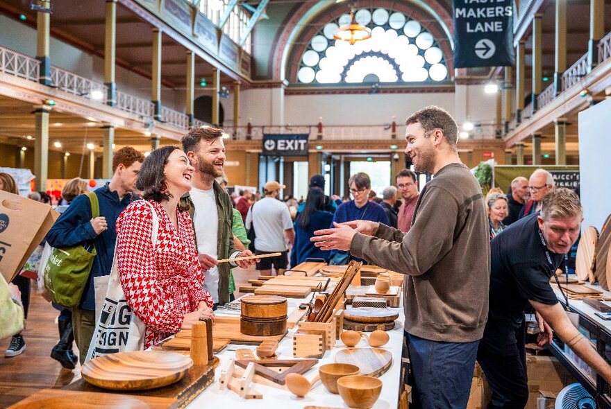 People browsing a designer craft stall and talking to the stallholder at the Big Design Market inside the Royal Exhibition Building.