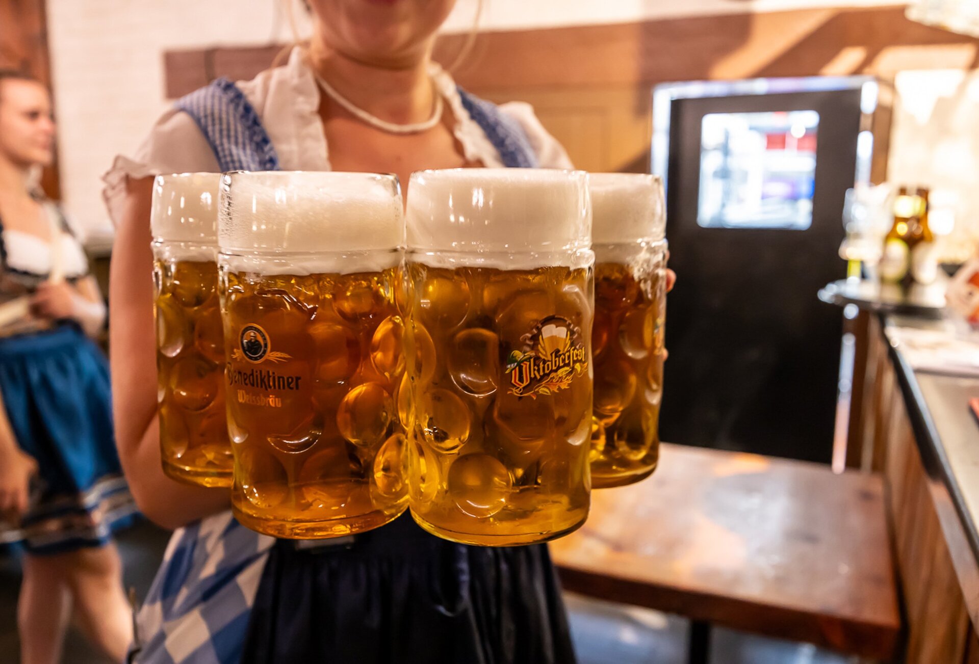 A barmaid is carrying four steins of German beer