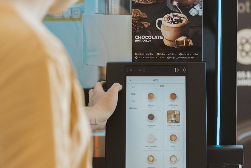 A person ordering a coffee by selecting an option on a touch screen.