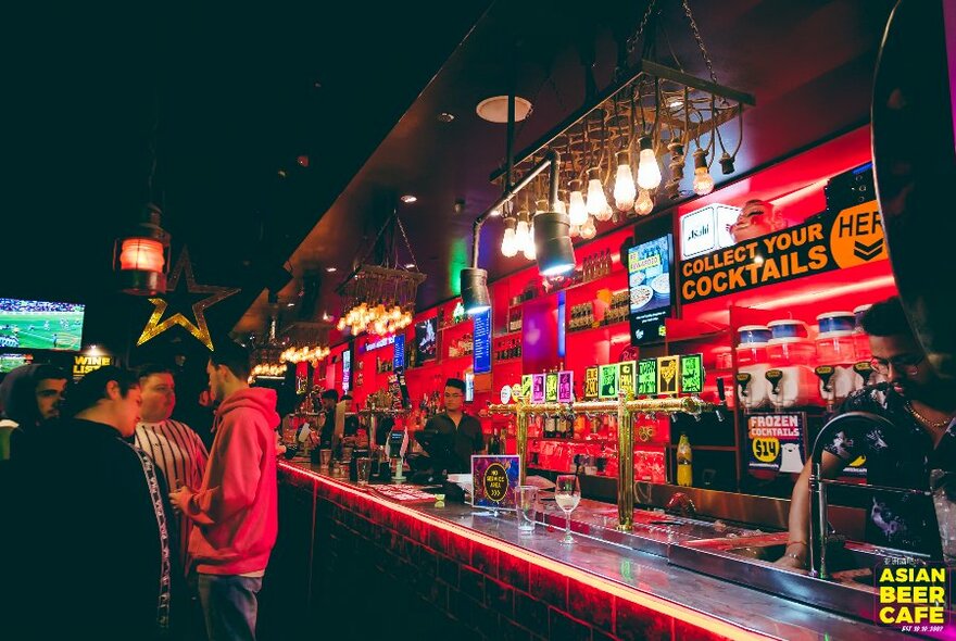 Colourful bar with posters on the wall behind the taps.