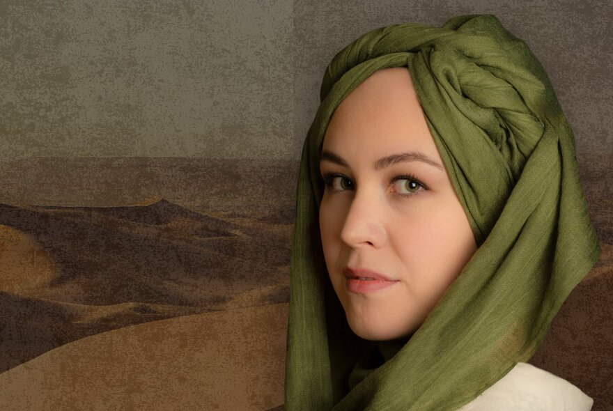 A woman with her face turned side on wearing an olive green head scarf with a grainy painting of the desert behind her.