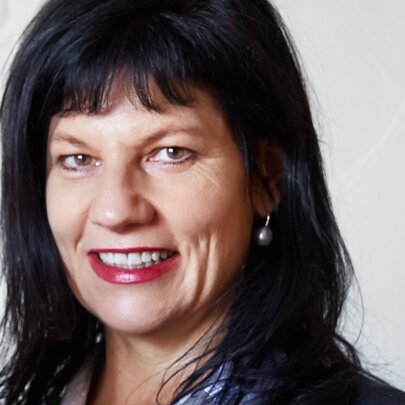 Author Jane Godwin, a woman with dark straight hair and a short fringe, smiling at the viewer, against a white background.