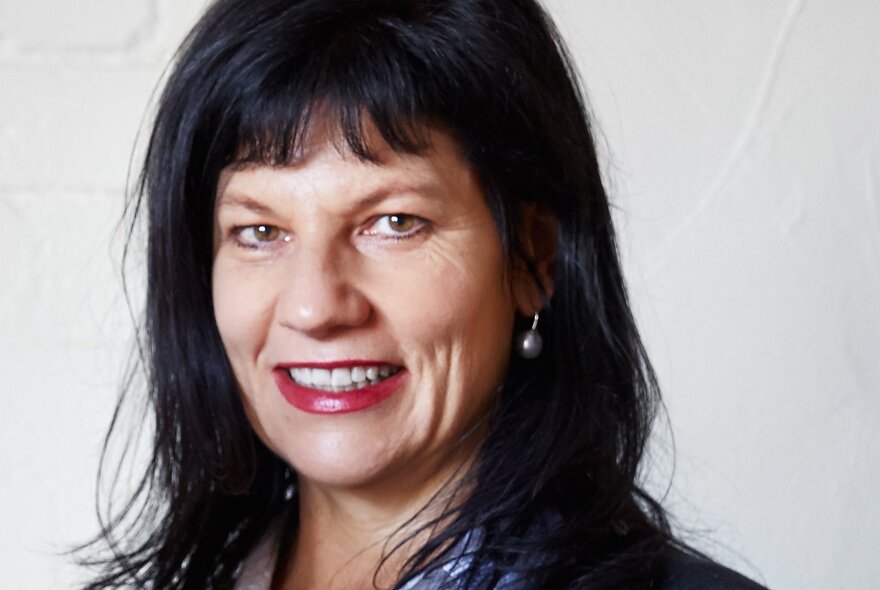 Author Jane Godwin, a woman with dark straight hair and a short fringe, smiling at the viewer, against a white background.