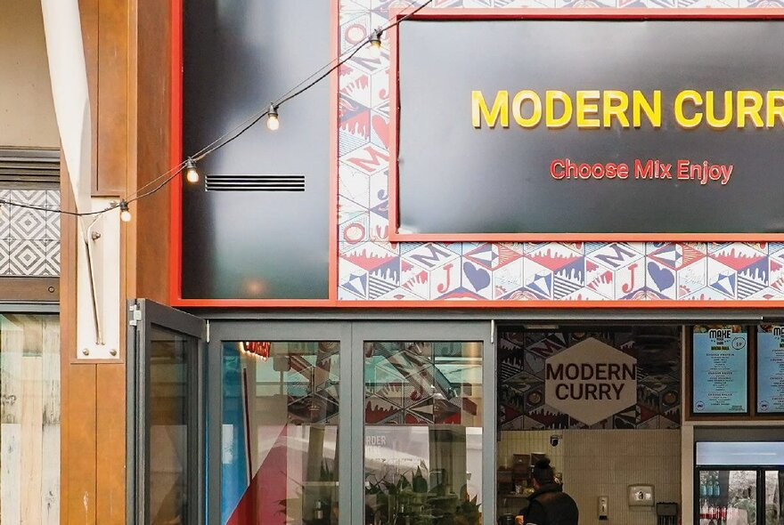The shopfront of Indian restaurant Modern Curry, with signage above glass entrance doors.