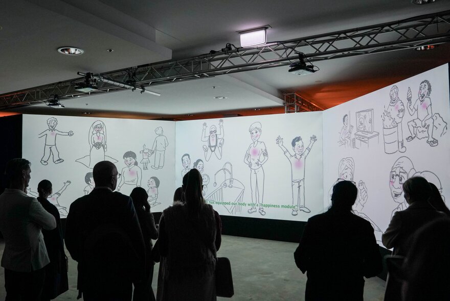 A crowd of people in a museum looking at a tri-panel hand drawn mural of people engaged in different activities.