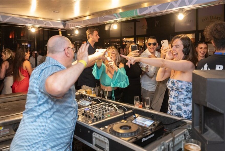 DJ being photographed by people holding phones in a bar setting.