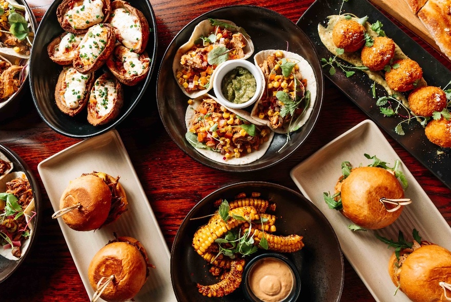 Grazing platters of food on a wooden table, seen from above.